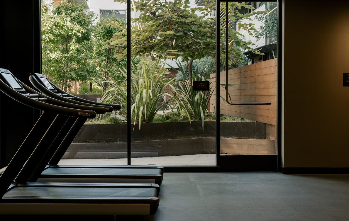Modern fitness center interior with exercise equipment such as treadmills and weight machines arranged in a bright, well-lit workout space, designed for resident wellness and workouts.