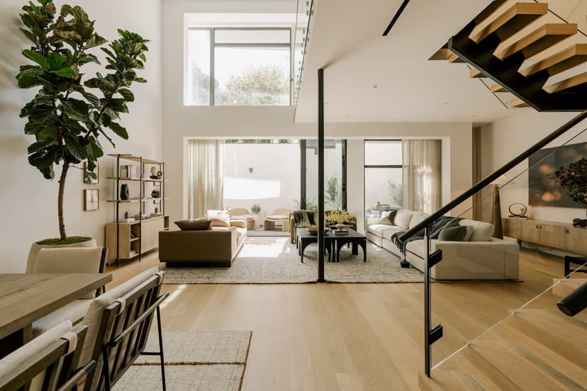Open plan kitchen and dining area in a luxury residence at The Harland West Hollywood, showing a sleek modern kitchen with integrated appliances, a central island or counter with seating, and a dining table with chairs set near large windows that let in natural light.