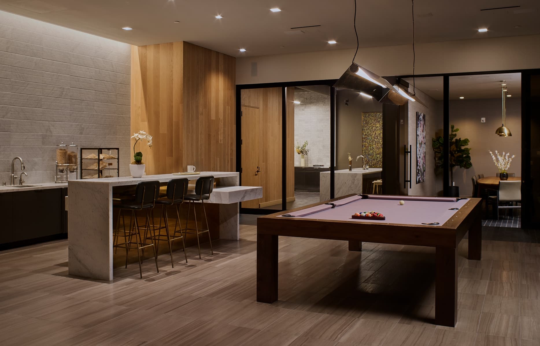 Entertainment lounge with pool table, lounge seating, and floor-to-ceiling windows in a modern residential building.