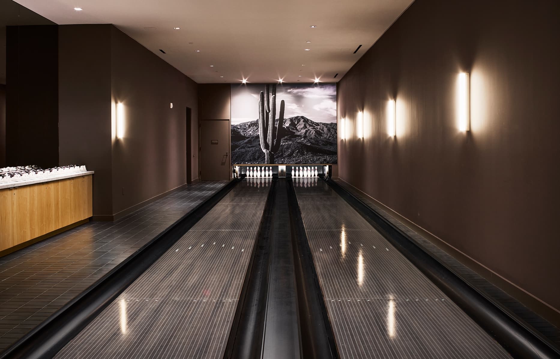 Two-lane bowling alley with modern design, polished lanes, and lounge seating at The Harland.