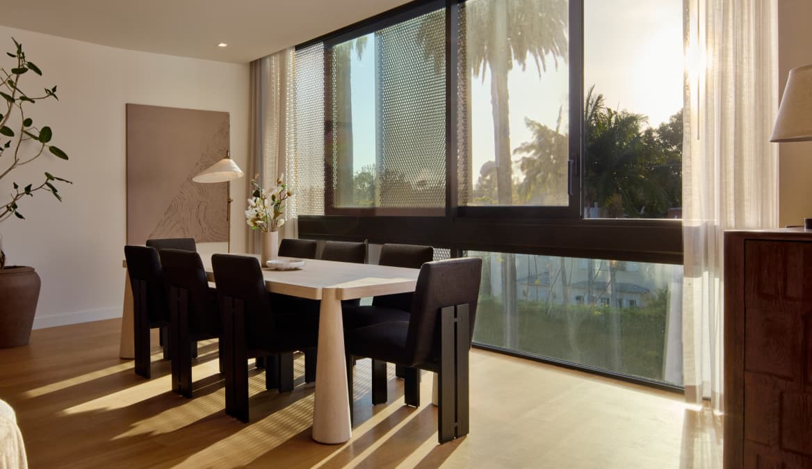 A dining room within a modern residence at The Harland, featuring a central dining table surrounded by chairs. The space is designed with a minimalist, contemporary aesthetic and is likely positioned near the kitchen or living area, supporting both everyday meals and entertaining.